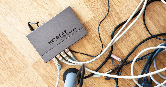 Bilden föreställer kabelspaghetti omkring en netgear-switch på golvet